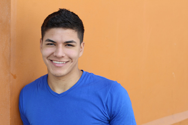Joven sonriendo mientras se apoya en una pared